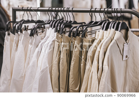 Close-up of hangers with casual youth clothing in store, natural fabrics and colors Close-up of hangers with casual youth clothing in store, natural fabrics and colors 90069966