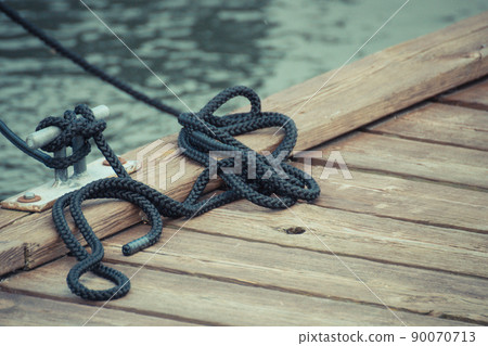 Black rope on bridge as part of yacht anchor. Detail of sailboat Black rope on bridge as part of yacht anchor. Detail of sailboat 90070713