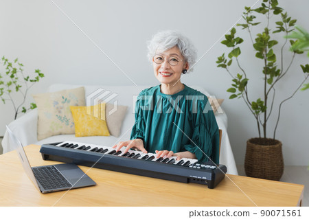 Gray-haired woman playing the keyboard in the living room 90071561