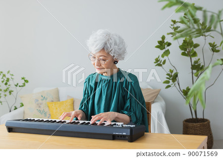 在客廳裡彈鍵盤的灰髮女人 90071569