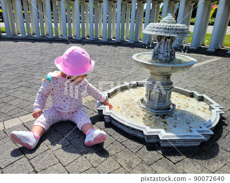 Little charming girl in a pink panama at the fountain with coins in summer 90072640