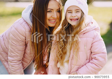 Family in a summer park. Mother in a pink jacket. Little girl walks in a park. Family in a summer park. Mother in a pink jacket. Little girl walks in a park. 90073955