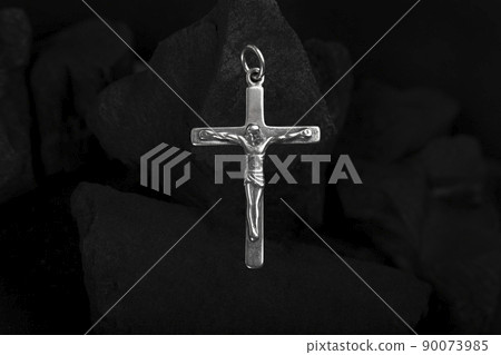 Silver crucifix necklace cross on pieces of coal. Silver crucifix necklace cross on pieces of coal. 90073985