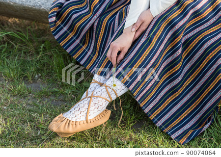 Leather bast shoes of a Latvian woman in traditional clothing. Preparing Ligo festival. Riga. Latvia Leather bast shoes of a Latvian woman in traditional clothing. Preparing Ligo festival. Riga. Latvia 90074064