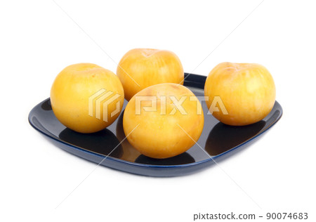 Yellow plums on a dark blue plate, isolated on a white background Yellow plums on a dark blue plate, isolated on a white background 90074683