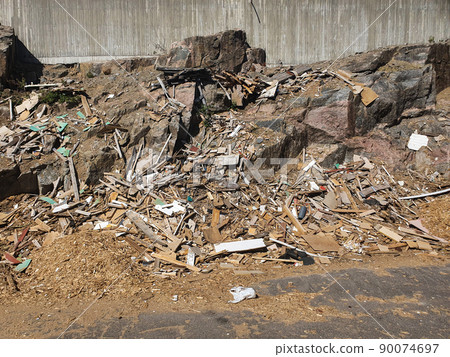 a stone wall in a garbage dump. wooden waste in a landfill. a stone wall in a garbage dump. wooden waste in a landfill. 90074697