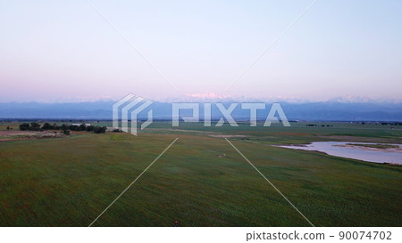 Sunset in a field with mountain and lake views. Sunset in a field with mountain and lake views. 90074702