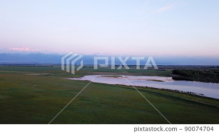 Sunset in a field with mountain and lake views. Sunset in a field with mountain and lake views. 90074704