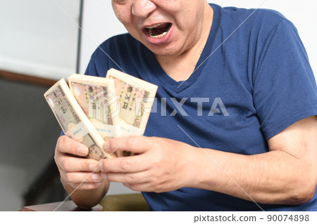 A smiling senior man with a wad of bills A smiling senior man with a wad of bills 90074898