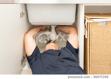 man fixing the sink siphon in the laundry room with his own hands man fixing the sink siphon in the laundry room with his own hands 90075399
