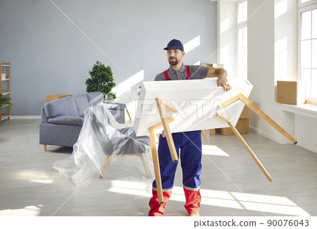 Young man from moving company or truck delivery service removing table from apartment Young man from moving company or truck delivery service removing table from apartment 90076043