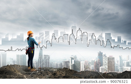 Female engineer in hard hat with blueprint 90076321