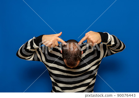 Human alopecia or hair loss - adult man hands pointing at his bald head isolated on blue studio background. Human alopecia or hair loss - adult man hands pointing at his bald head isolated on blue studio background. 90076443