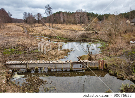 Old wooden footbridge over Ikva river in Western Ukraine. 90076632