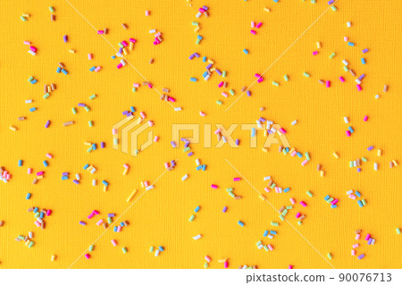 Colorful sprinkles on yellow background. Concept of fun and celebration. Spring, summer mood. Confectionery decorating ingredients on paper making pattern. Backdrop for party invitation card design Colorful sprinkles on yellow background. Concept of fun and celebration. Spring, summer mood. Confectionery decorating ingredients on paper making pattern. Backdrop for party invitation card design 90076713