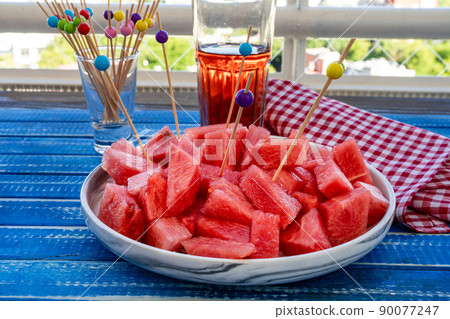 Jagged little pieces of fresh sweet watermelon on a serving platter with chopsticks. Healthy, fresh and natural food. Season fruits. Jagged little pieces of fresh sweet watermelon on a serving platter with chopsticks. Healthy, fresh and natural food. Season fruits. 90077247