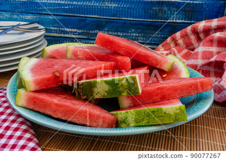 Heap of triangular pieces of a cold and delicious watermelon prepared to serve on a large plate. Healthy, fresh and natural food. Season fruits. Heap of triangular pieces of a cold and delicious watermelon prepared to serve on a large plate. Healthy, fresh and natural food. Season fruits. 90077267