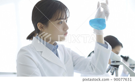 一個穿著白大褂的女人盯著燒瓶研究實驗 90077631