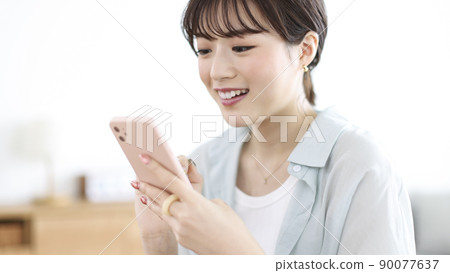 Young woman smartphone looking at smartphone Young woman smartphone looking at smartphone 90077637