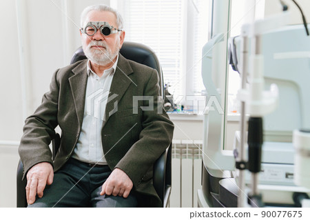 making a selection of lenses, diagnosing a elderly man's vision. 90077675