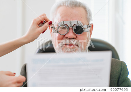 making a selection of lenses, diagnosing a elderly man's vision. making a selection of lenses, diagnosing a elderly man's vision. 90077693