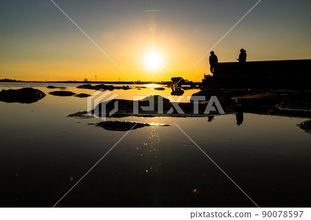 People playing on the beach at dusk 90078597