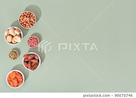 Mix of dried fruits and nuts in bowls - symbols of judaic holiday Tu Bishvat. green background, copy space. Mix of dried fruits and nuts in bowls - symbols of judaic holiday Tu Bishvat. green background, copy space. 90078746