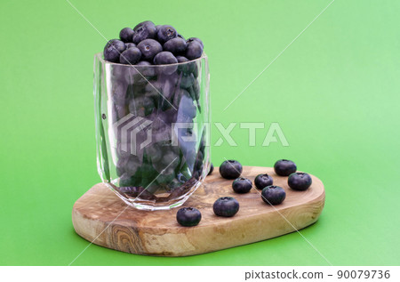 clear glass bowl full of ripe blueberries isolated on green clear glass bowl full of ripe blueberries isolated on green 90079736