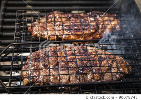 Selective focus of juicy beef steaks grilling on barbecue grid with smoke Selective focus of juicy beef steaks grilling on barbecue grid with smoke 90079743