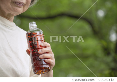 Senior woman drinking a bottle of drink in nature Senior woman drinking a bottle of drink in nature 90080318