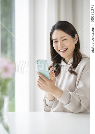 A smiling woman in her early 50s with a smartphone 90081372