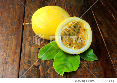 yellow passion fruit with leaf and passion fruit cut in half on wooden table 90082535