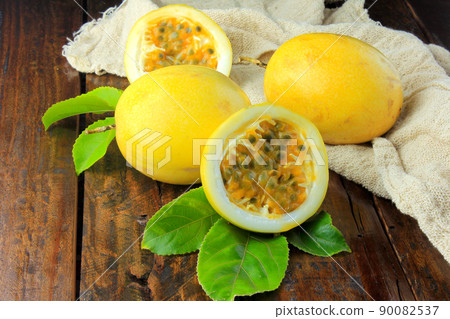 yellow passion fruit with leaf on sack and passion fruit cut in half on wooden table 90082537