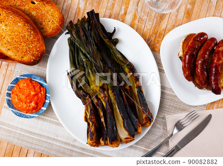 Appetizing calsot served with Romesco sauce and sausage butifarra Appetizing calsot served with Romesco sauce and sausage butifarra 90082882