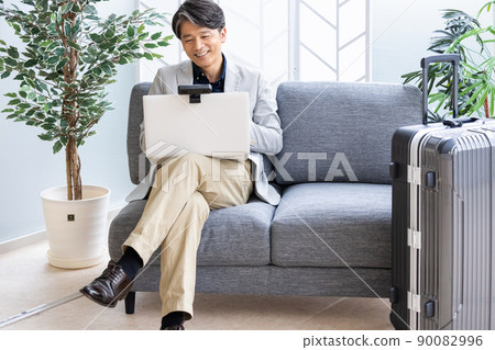 一位商人在出差時在沙發上進行遠程工作 90082996