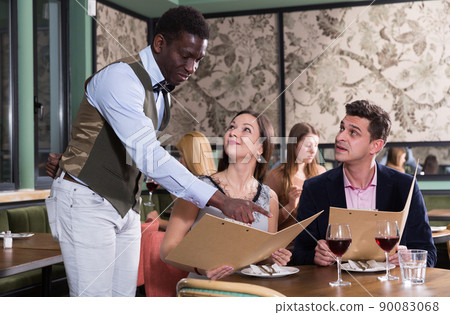 African American waiter helping couple with menu African American waiter helping couple with menu 90083068