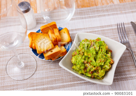 Guacamole with dry bread served on plate in restaurant 90083101