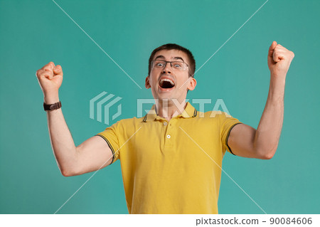 Handsome guy in a yellow casual t-shirt is posing over a blue background. Handsome guy in a yellow casual t-shirt is posing over a blue background. 90084606