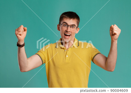 Handsome guy in a yellow casual t-shirt is posing over a blue background. 90084609