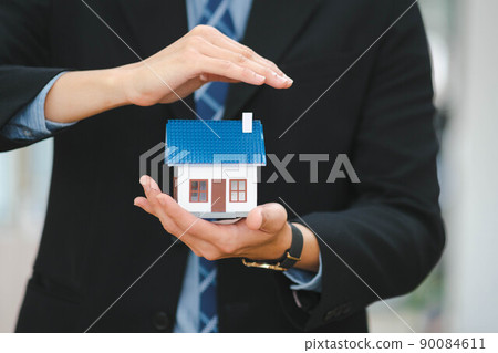 Businessman holding a house model. Businessman holding a house model. 90084611
