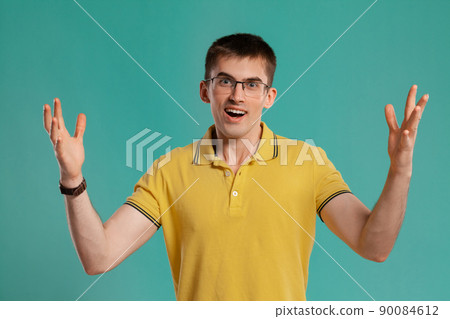 Handsome guy in a yellow casual t-shirt is posing over a blue background. Handsome guy in a yellow casual t-shirt is posing over a blue background. 90084612