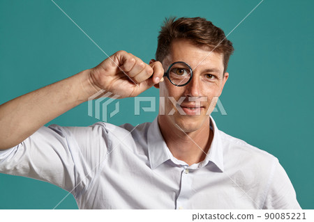 Young man in a classic white shirt is posing over a blue background. 90085221