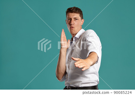 Young man in a classic white shirt is posing over a blue background. 90085224