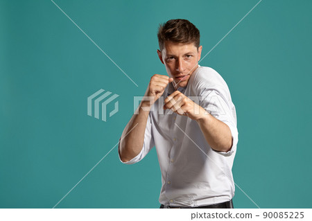 Portrait of a young brunet man posing in a studio against a blue background. 90085225