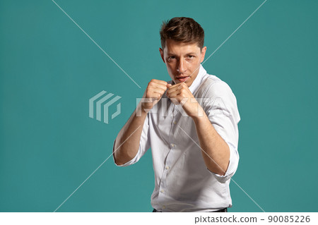 Portrait of a young brunet man posing in a studio against a blue background. 90085226