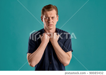 Close-up portrait of a ginger guy in navy t-shirt posing on blue background. Sincere emotions. Close-up portrait of a ginger guy in navy t-shirt posing on blue background. Sincere emotions. 90085432