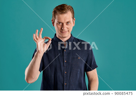 Close-up portrait of a ginger guy in navy t-shirt posing on blue background. Sincere emotions. Close-up portrait of a ginger guy in navy t-shirt posing on blue background. Sincere emotions. 90085475