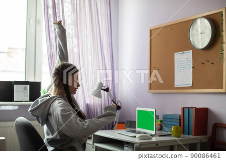 Green screen. While homeschooling, a girl stretches for a moment of relaxation. 90086461
