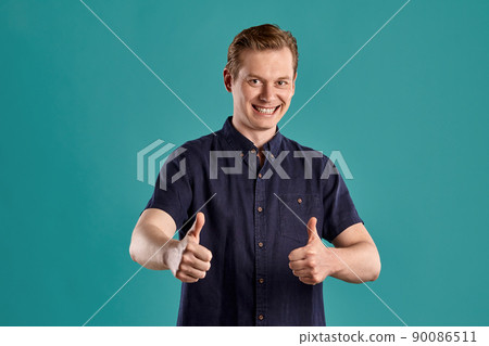 Close-up portrait of a ginger guy in navy t-shirt posing on blue background. Sincere emotions. 90086511