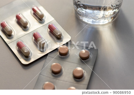 Medicine and a glass of water placed on the table by the window 90086950